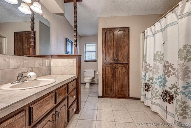 bathroom with vanity, toilet, a textured ceiling, and backsplash