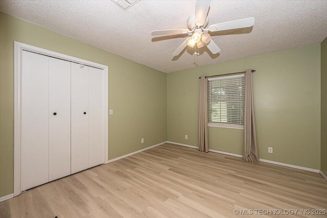 unfurnished bedroom featuring a closet, ceiling fan, light hardwood / wood-style floors, and a textured ceiling