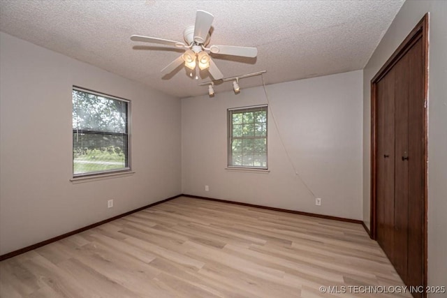 spare room with a healthy amount of sunlight, light hardwood / wood-style flooring, and a textured ceiling