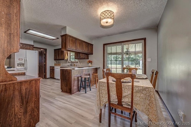 dining area with a textured ceiling and light wood-type flooring