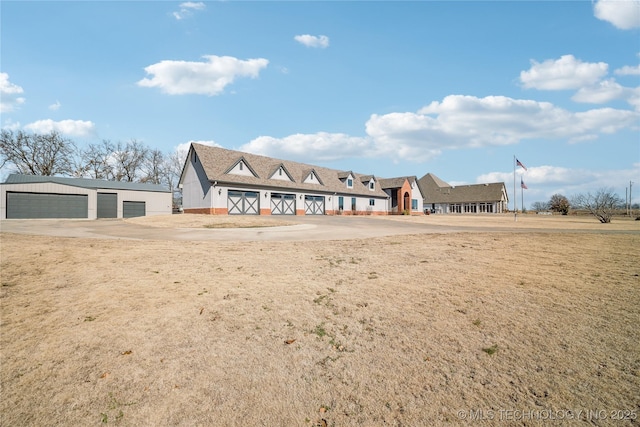 view of front of property with a garage, an outdoor structure, and a front lawn