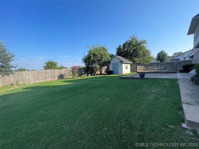 view of yard featuring an outbuilding, a patio, a storage unit, and a fenced backyard