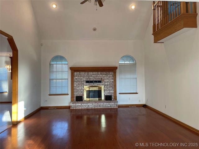 unfurnished living room featuring high vaulted ceiling, a brick fireplace, ceiling fan, and wood finished floors