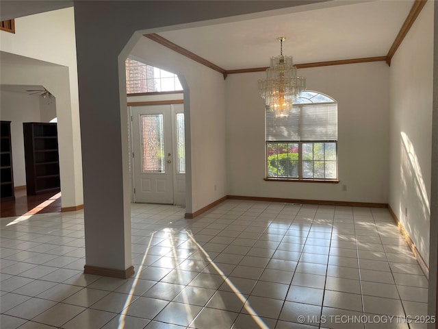 foyer entrance with light tile patterned floors, baseboards, arched walkways, and crown molding