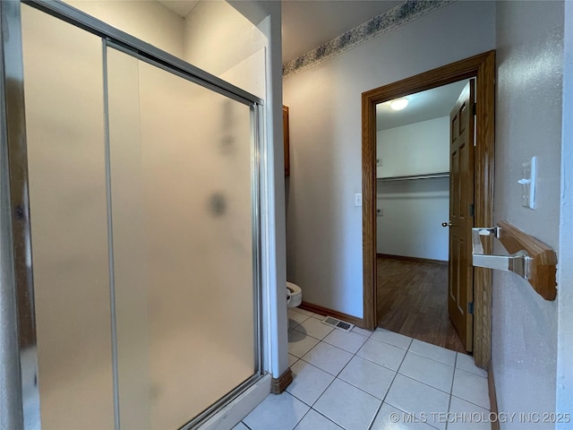 bathroom featuring visible vents, a spacious closet, a shower stall, tile patterned flooring, and baseboards