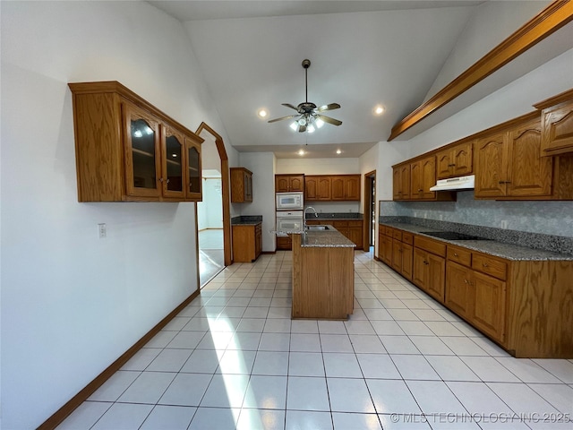 kitchen with glass insert cabinets, brown cabinets, stainless steel microwave, and an island with sink