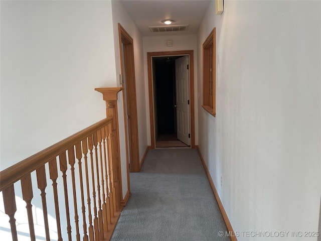 hall with carpet floors, an upstairs landing, visible vents, and baseboards