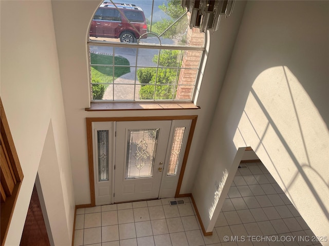 tiled entrance foyer featuring a high ceiling, visible vents, and baseboards