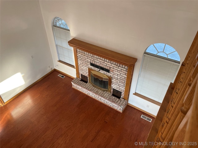 unfurnished living room featuring a fireplace, wood finished floors, and visible vents