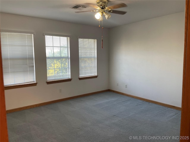 carpeted empty room with ceiling fan, visible vents, and baseboards