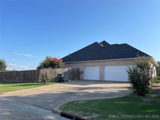 view of home's exterior featuring brick siding, roof with shingles, fence, a garage, and driveway