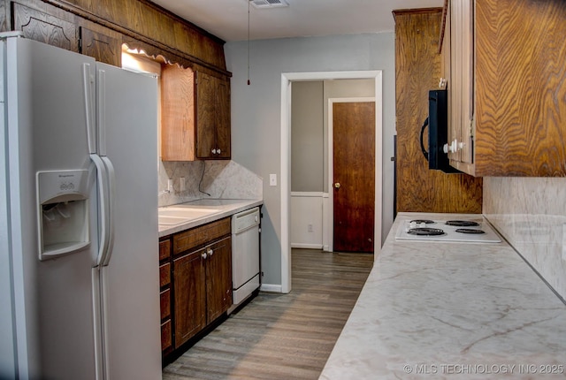 kitchen featuring backsplash, white appliances, dark wood-type flooring, and sink