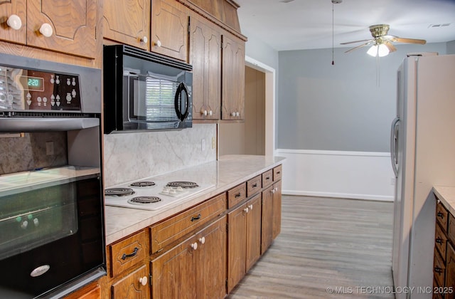 kitchen with tasteful backsplash, light wood-type flooring, ceiling fan, and black appliances