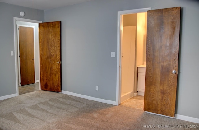 unfurnished bedroom with light colored carpet and connected bathroom