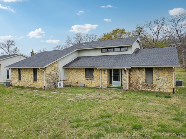 view of front facade featuring a front lawn, stone siding, and roof with shingles