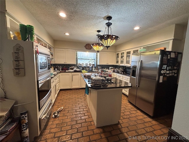 kitchen with pendant lighting, white cabinets, a center island, stainless steel appliances, and a textured ceiling