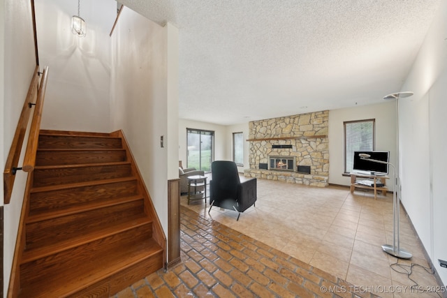 stairs with a stone fireplace and a textured ceiling
