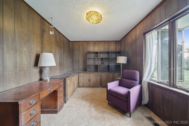 home office featuring a textured ceiling, wood walls, and visible vents