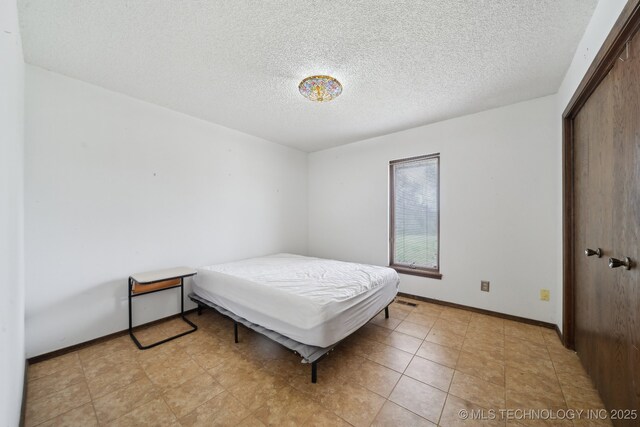 bedroom with a textured ceiling, a closet, and baseboards