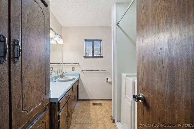 full bath featuring tile patterned floors, vanity, baseboards, and a textured ceiling