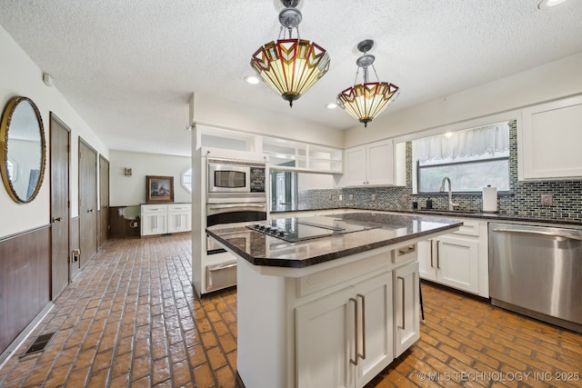 kitchen with visible vents, a sink, appliances with stainless steel finishes, white cabinetry, and decorative backsplash