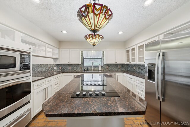 kitchen with stainless steel appliances, a center island, a textured ceiling, and decorative backsplash