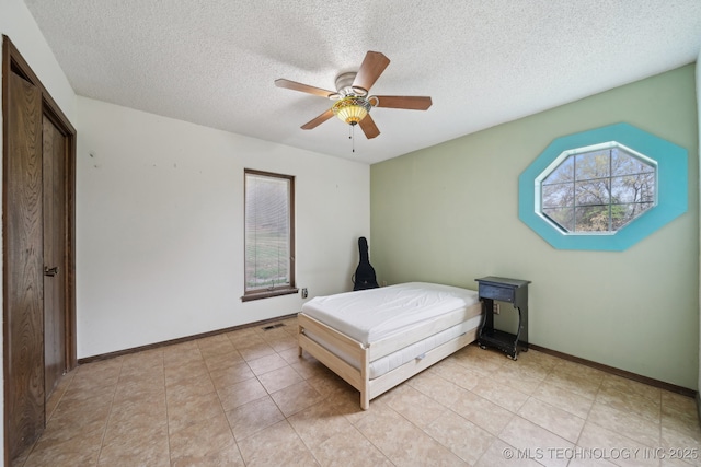 bedroom with a textured ceiling, ceiling fan, multiple windows, and visible vents