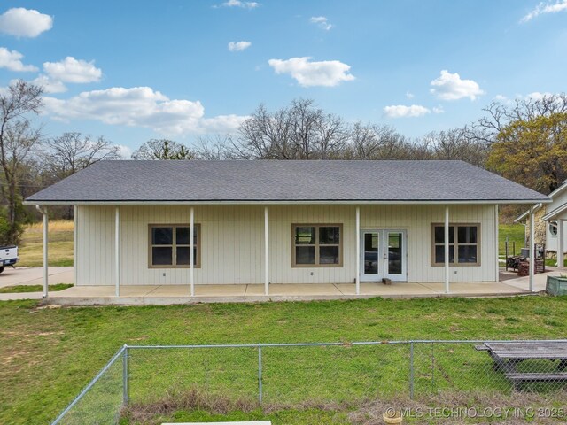 back of house featuring a patio, a lawn, french doors, fence, and a shingled roof
