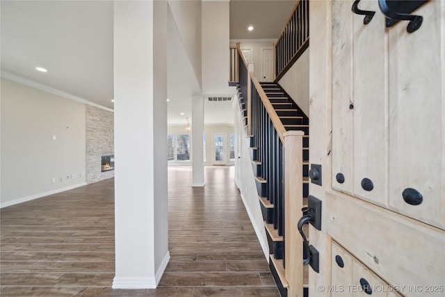 entrance foyer featuring ornamental molding, dark hardwood / wood-style floors, and a fireplace