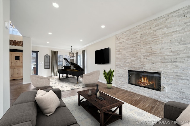 living room with light hardwood / wood-style flooring, a notable chandelier, a fireplace, and ornamental molding