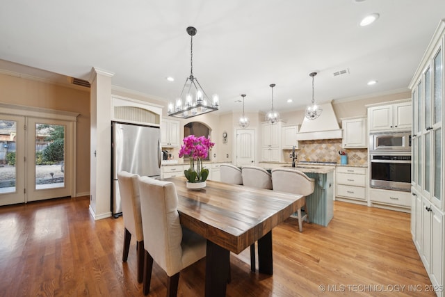 dining room featuring crown molding, sink, and light hardwood / wood-style flooring