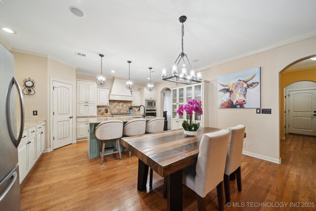 dining area with ornamental molding and light hardwood / wood-style flooring