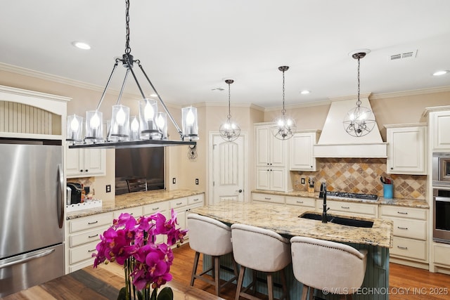 kitchen featuring a kitchen island with sink, decorative light fixtures, light stone countertops, and appliances with stainless steel finishes