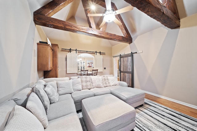 living room featuring ceiling fan, a barn door, hardwood / wood-style floors, and beam ceiling