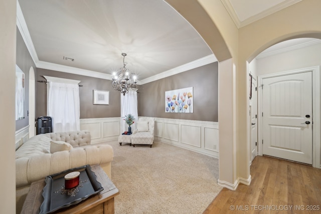 living room featuring crown molding, a notable chandelier, and light hardwood / wood-style floors