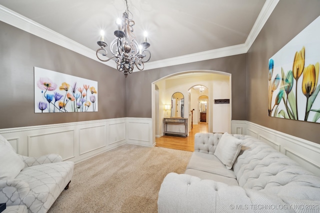 carpeted living room featuring an inviting chandelier and crown molding