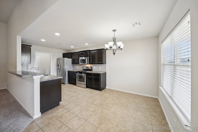 kitchen featuring sink, an inviting chandelier, hanging light fixtures, stainless steel appliances, and decorative backsplash