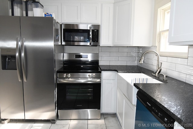 kitchen with dark stone countertops, stainless steel appliances, and white cabinets