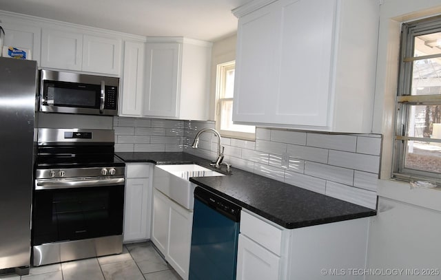 kitchen featuring white cabinetry, sink, light tile patterned floors, and appliances with stainless steel finishes