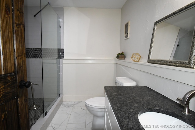 bathroom with tiled shower, vanity, and toilet