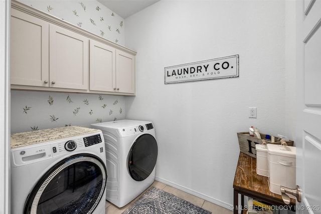 clothes washing area featuring cabinets, washer and dryer, and light tile patterned floors