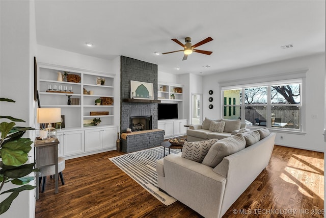 living room with dark hardwood / wood-style flooring, ceiling fan, a fireplace, and built in shelves