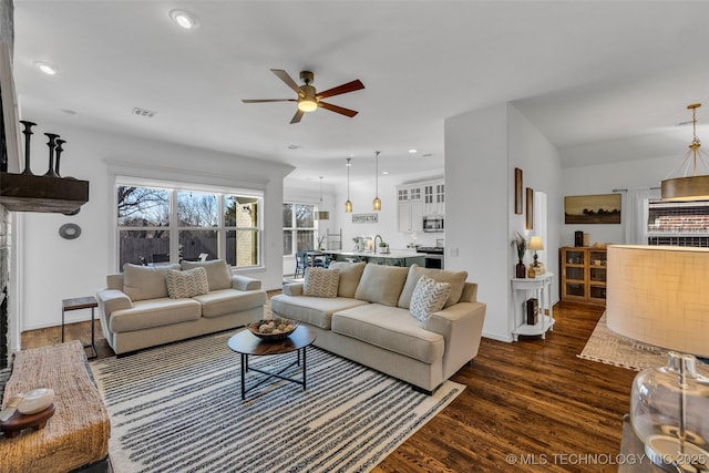 living room featuring ceiling fan and dark hardwood / wood-style flooring