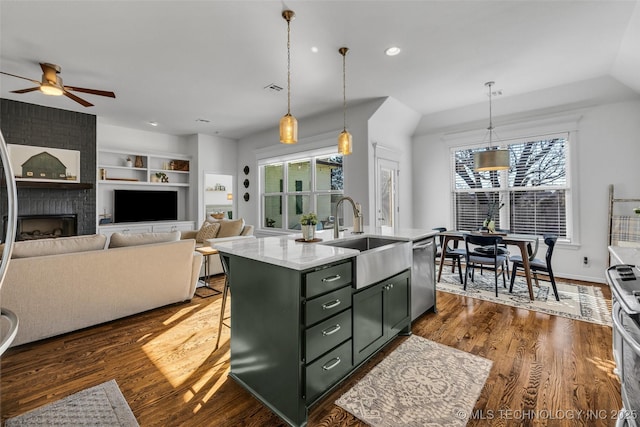 kitchen featuring stainless steel dishwasher, sink, a center island with sink, and decorative light fixtures