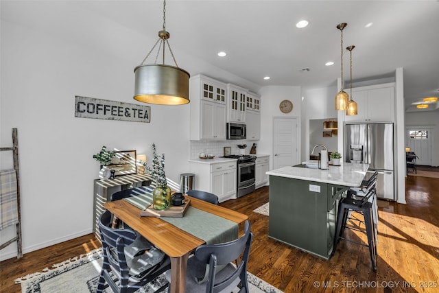 kitchen featuring stainless steel appliances, white cabinets, and a center island with sink