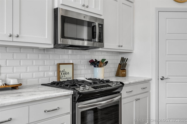 kitchen featuring tasteful backsplash, appliances with stainless steel finishes, light stone countertops, and white cabinets