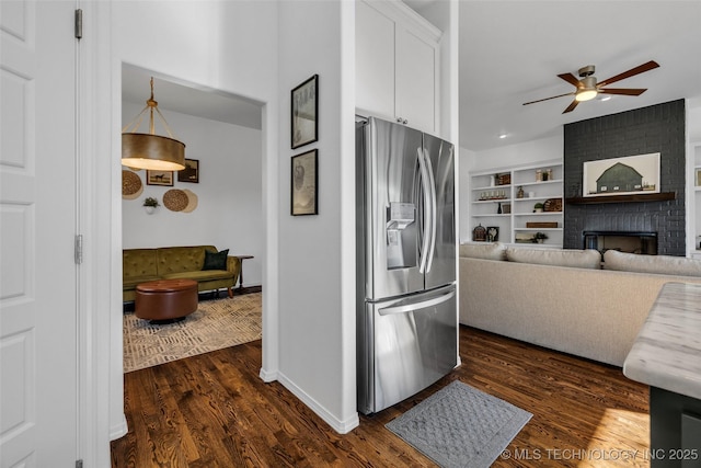 kitchen featuring a brick fireplace, stainless steel fridge, dark hardwood / wood-style floors, and white cabinets