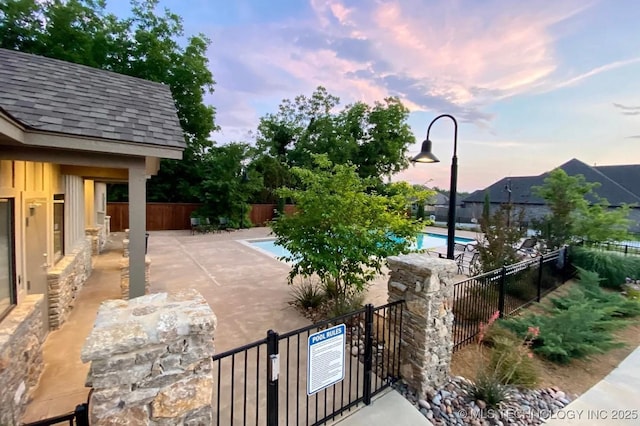 patio terrace at dusk featuring a community pool