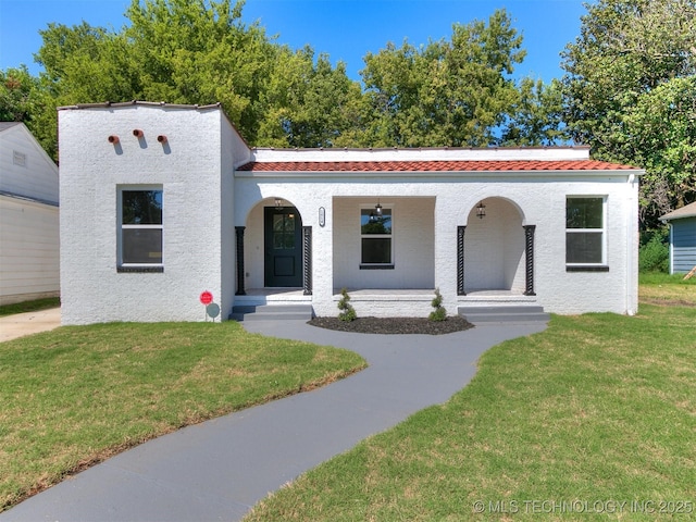 mediterranean / spanish-style house with a front lawn and covered porch