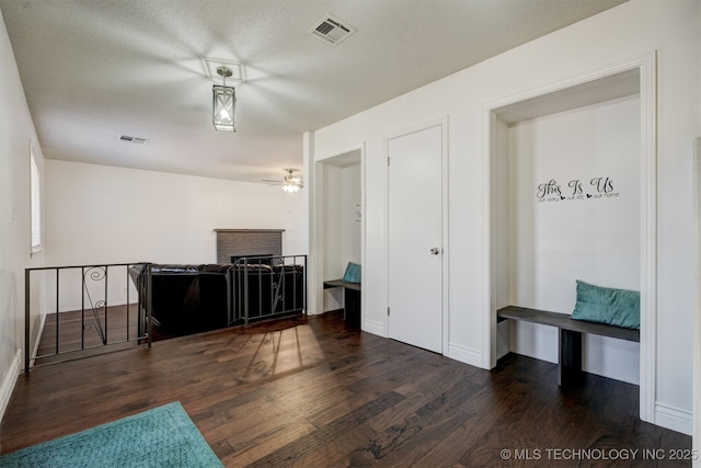 interior space featuring ceiling fan, dark wood-type flooring, a textured ceiling, and a fireplace